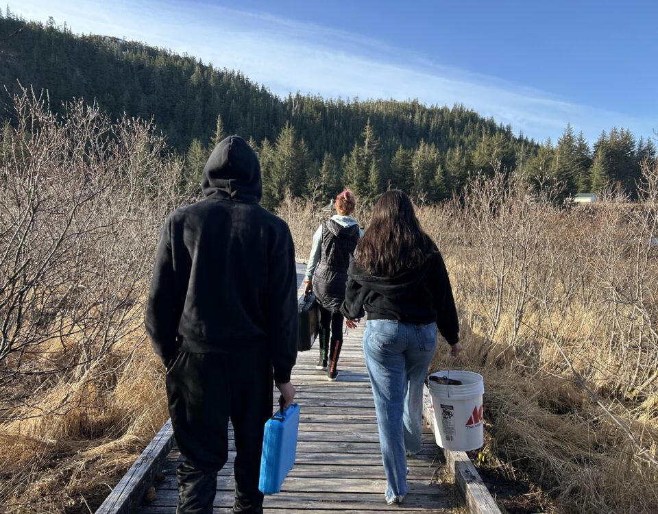 Cordova High School Environmental Science Class walking out to Odiak Pond in Cordova, AK with sampling equipment.