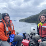One male and one female fish researcher sitting on a boat in the ocean