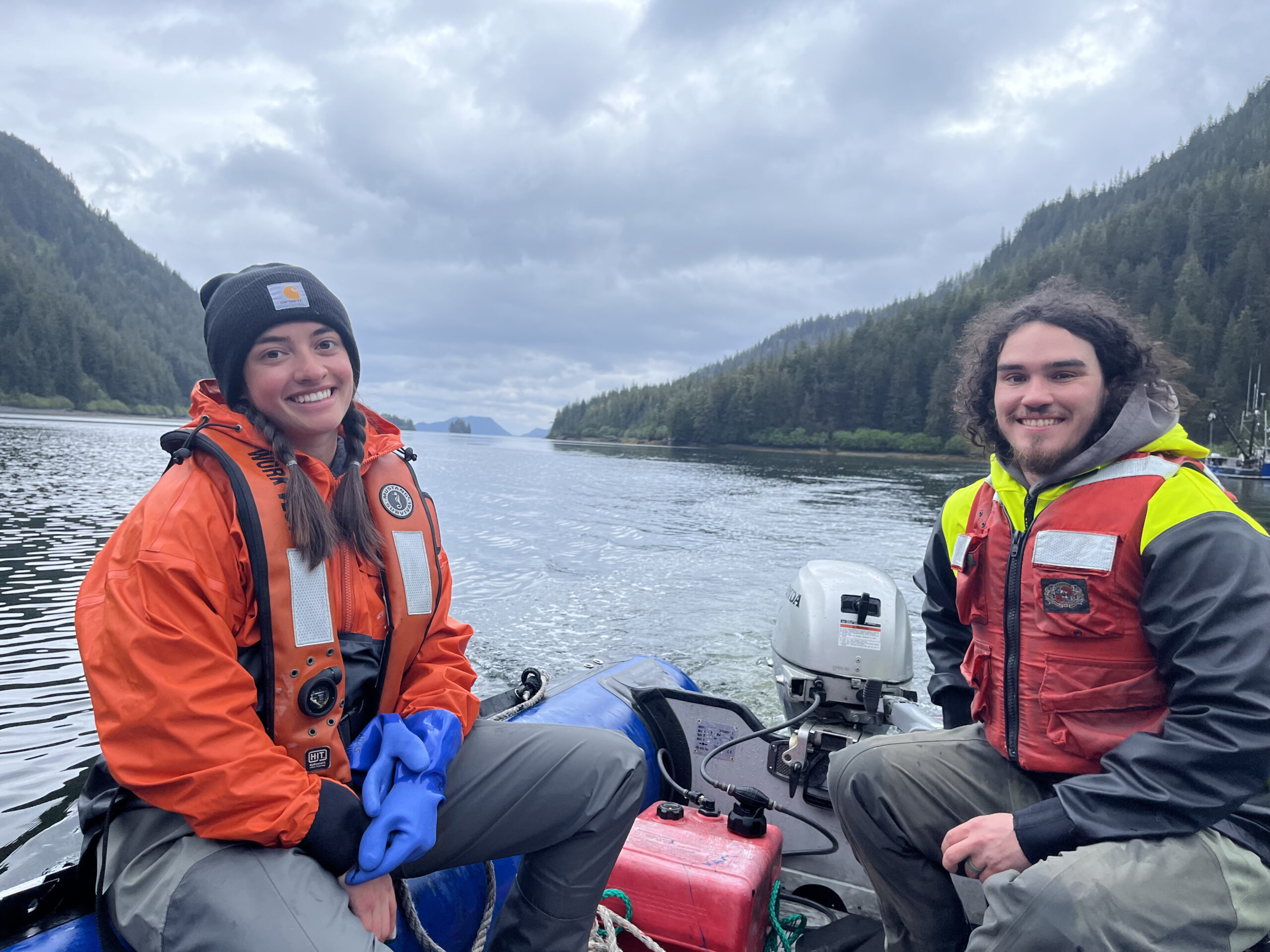 One male and one female fish researcher sitting on a boat in the ocean