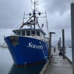 big blue boat sitting on the water tied up to the harbor