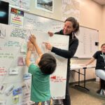 woman helps young boy learn about salmon