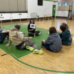 four high school students gather around woman to learn about bird monitoring