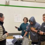 Man teaches three high school students how to use scientific equipment