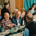 A group of guests at the CRN fundraiser at table 21 and 22 with volunteer servers ensuring all guests have drinks.